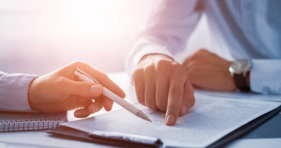 istockphoto-840610244-612x612 (1) Business people negotiating a contract. Human hands working with documents at desk and signing contract.